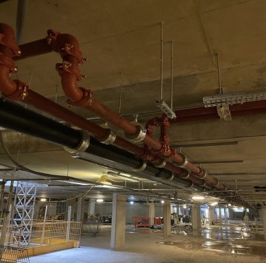Parallel pipework runs suspended beneath a concrete ceiling.