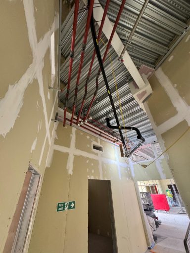 Pipework runs and connections above an unfinished interior.