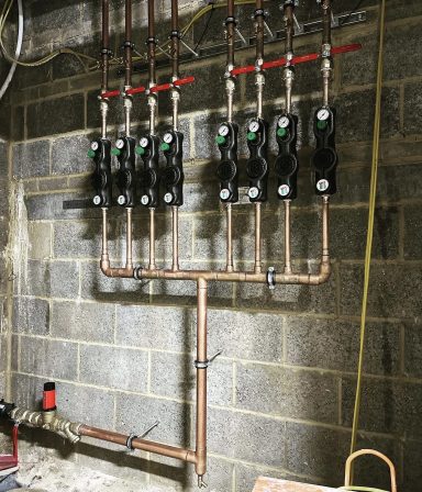 A row of wall-mounted pipework assemblies with valves and meters.