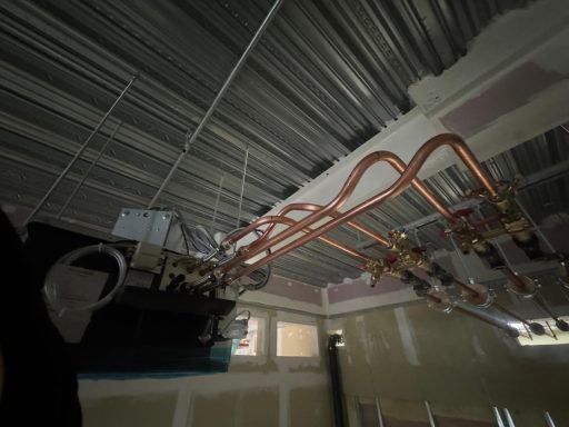 Copper pipework bends routed beneath a metal ceiling.