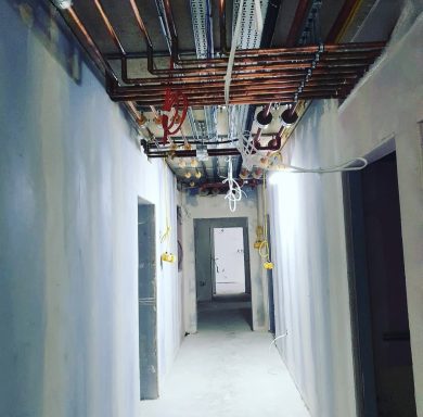 Overhead pipework installed along a commercial building corridor.